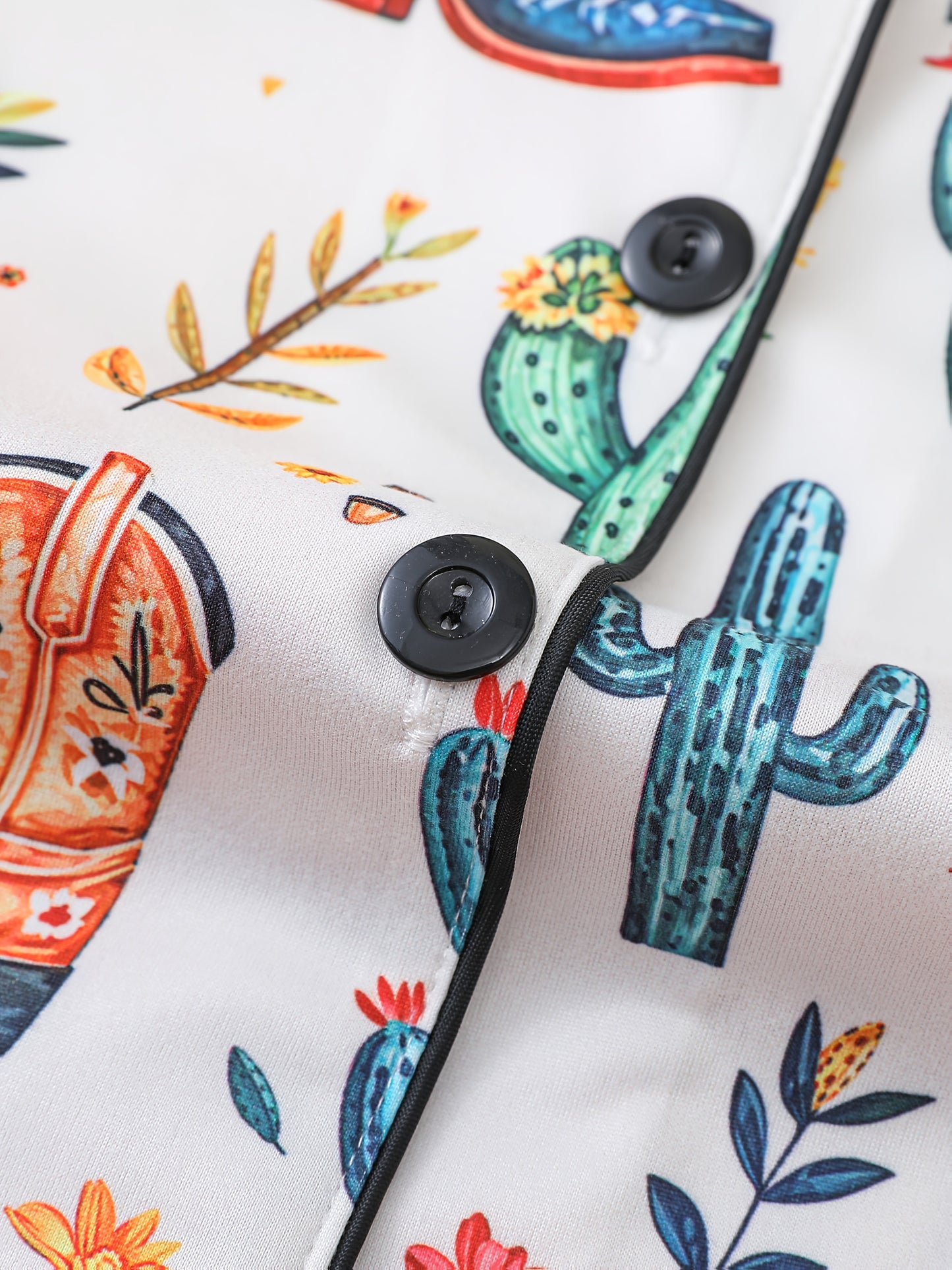 Ivory satin-look pajama set with watercolor cactus and floral print — close-up of glossy black buttons, contrast piping and smooth fabric (95% Polyester/5% Elastane)