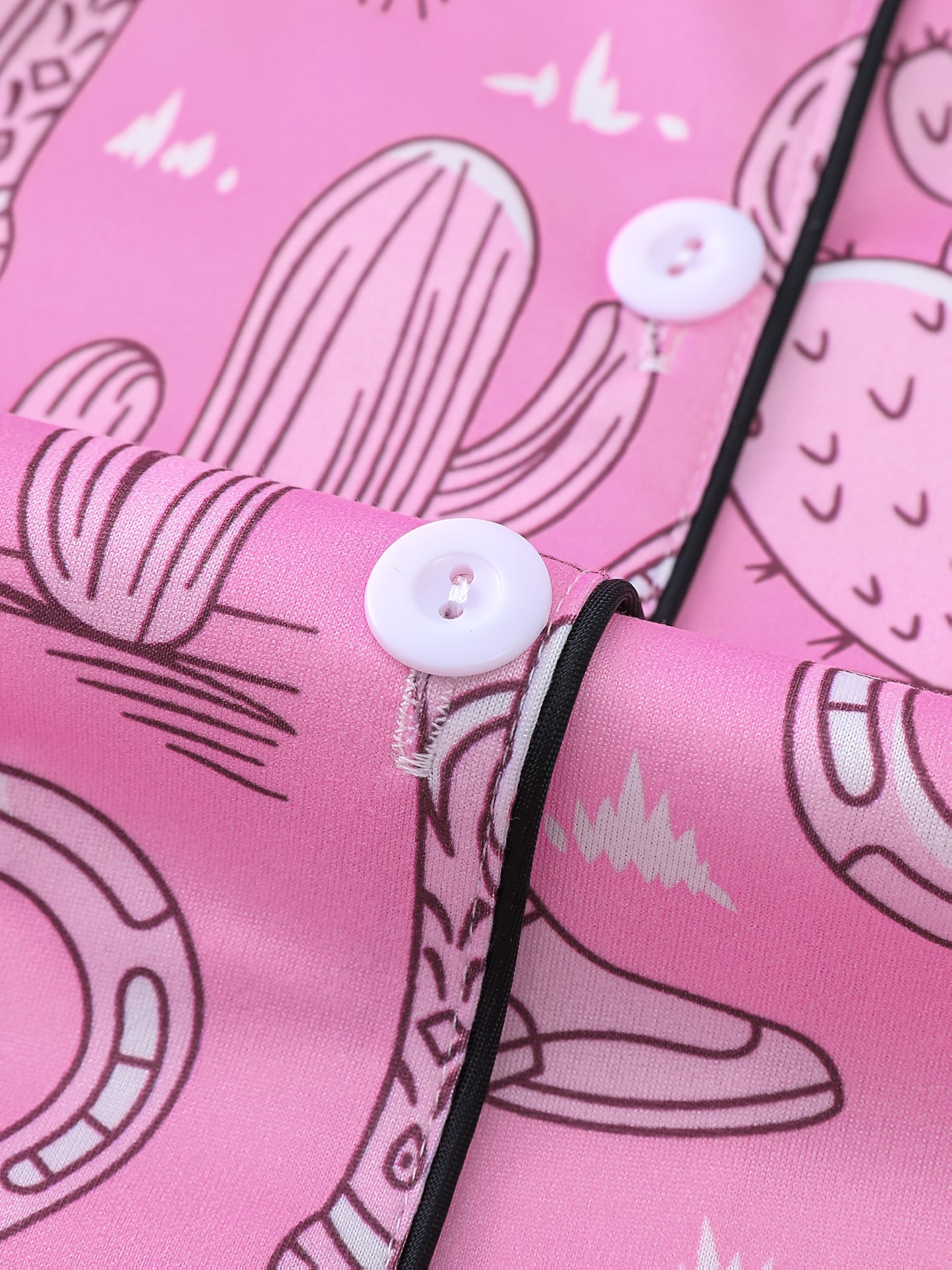 Bubblegum pink satin-look short pajama set with cowboy boots, hats and cactus print — button-up short-sleeve top with chest pocket and elastic waist shorts, 95% Polyester/5% Elastane