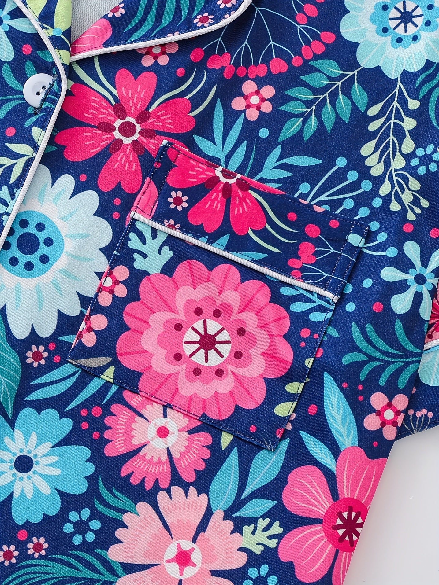 Navy satin-look pajama set with bright pink and aqua floral print — short-sleeve button-up top with chest pocket and elastic waist shorts, 95% Polyester/5% Elastane