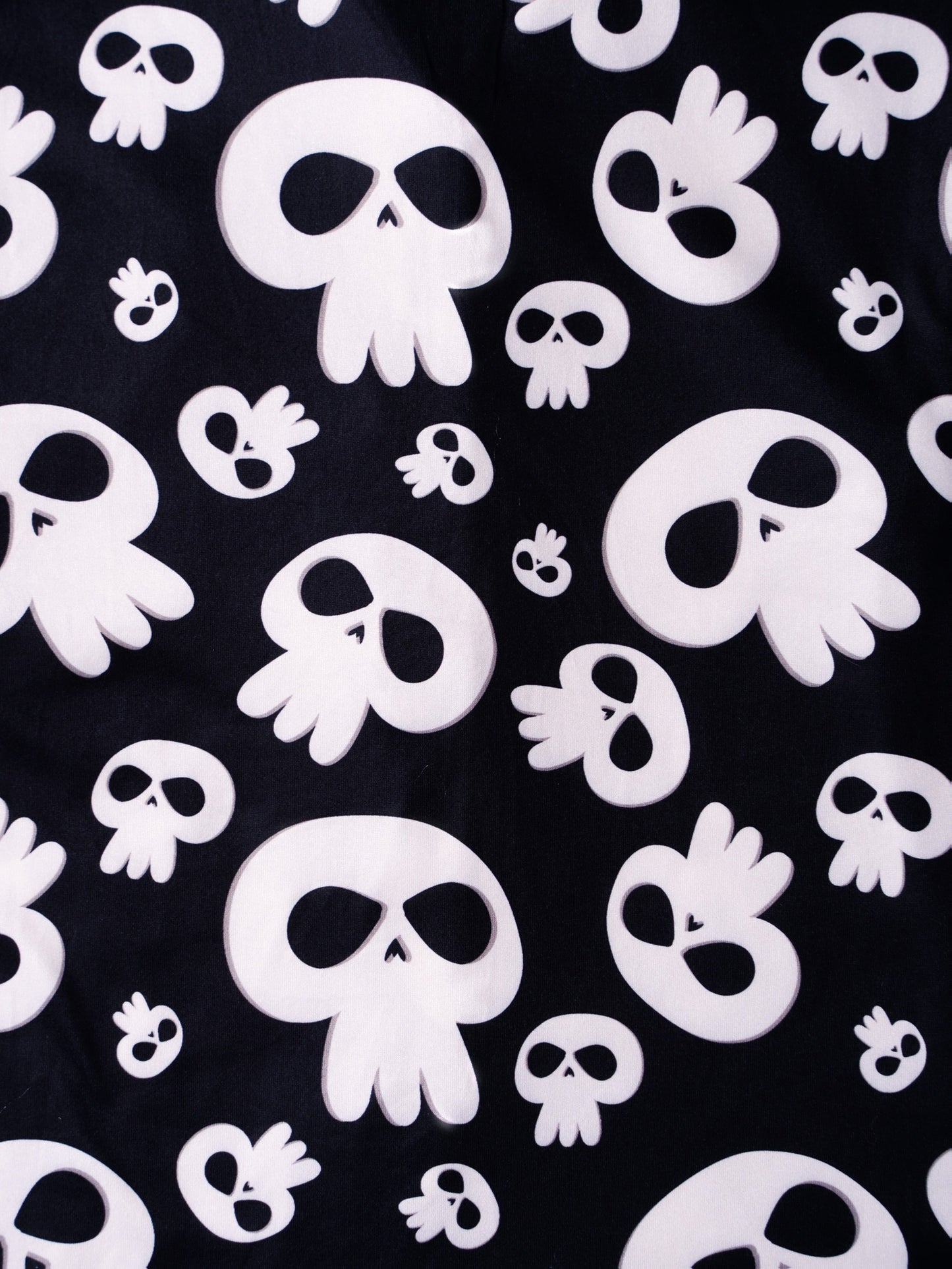 Black modal pajama set with cream skull motifs — short‑sleeve button top and elastic waist shorts with piping