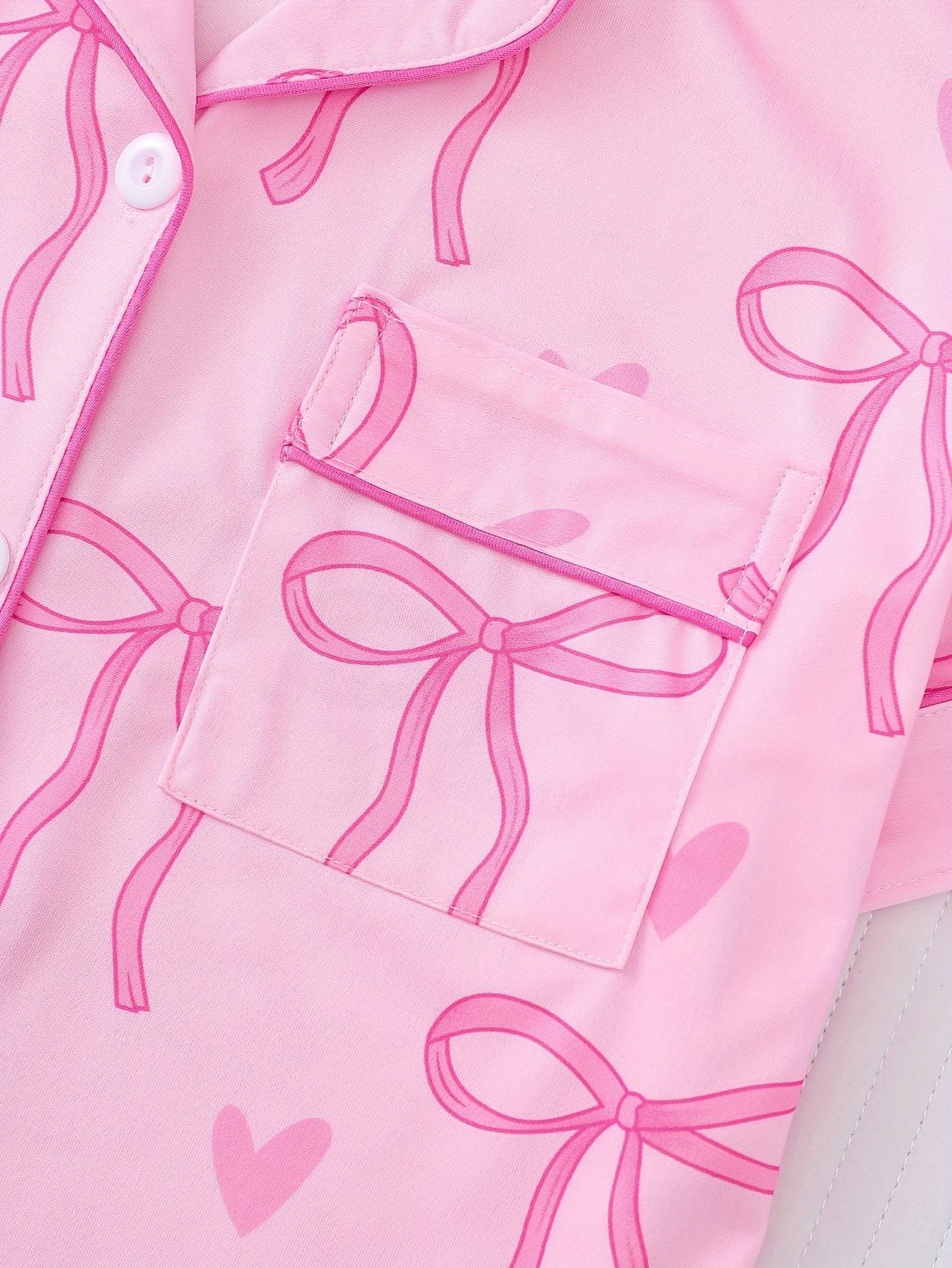 Pink satin-look short sleeve pajama set with bow print and hearts, piped trim, chest pocket and elastic waist shorts in 95% Polyester 5% Elastane — silky stretch loungewear