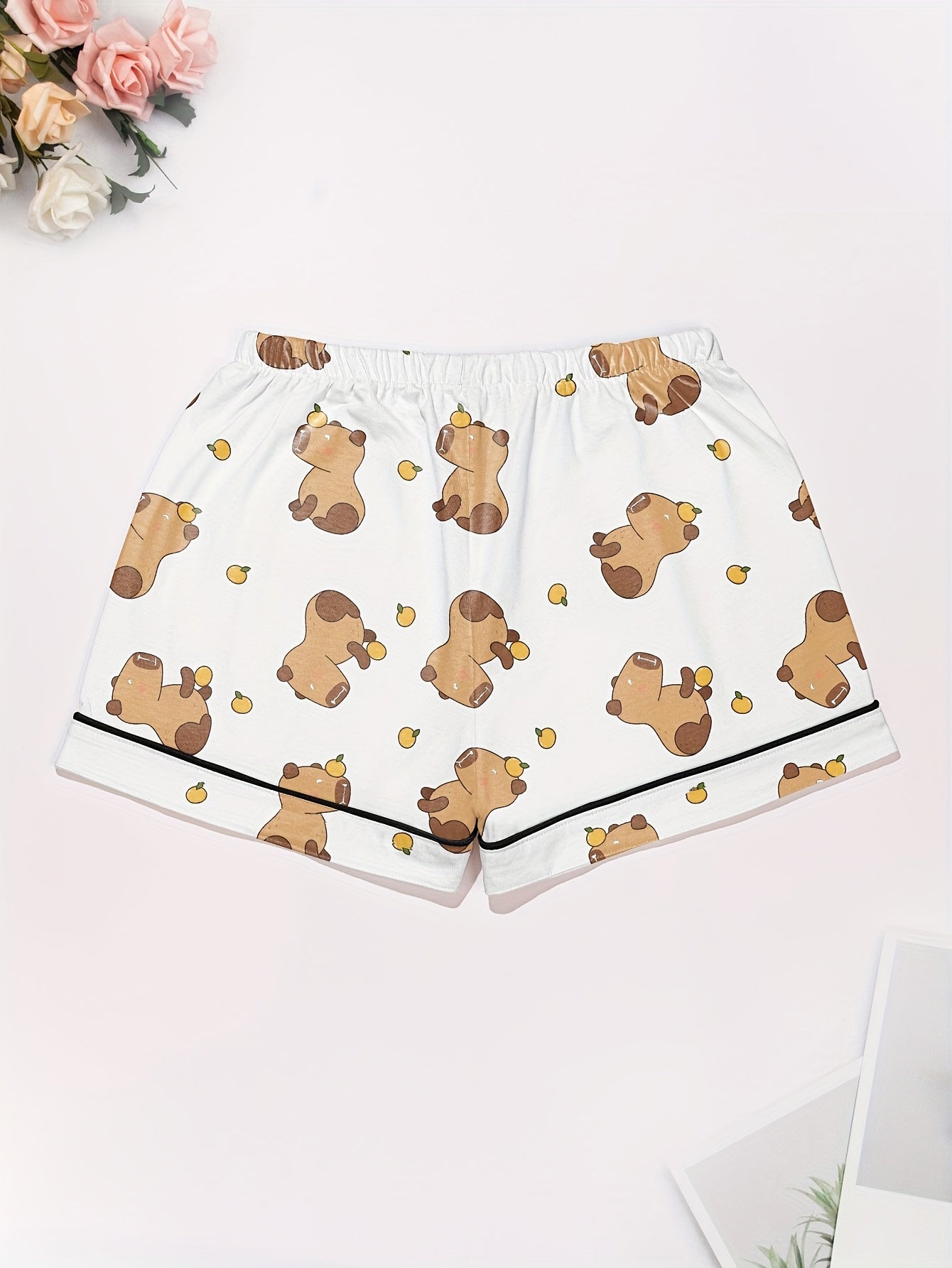 White short-sleeve pajama set with brown bear and yellow pear print — button-up top and elastic waist shorts with black piping