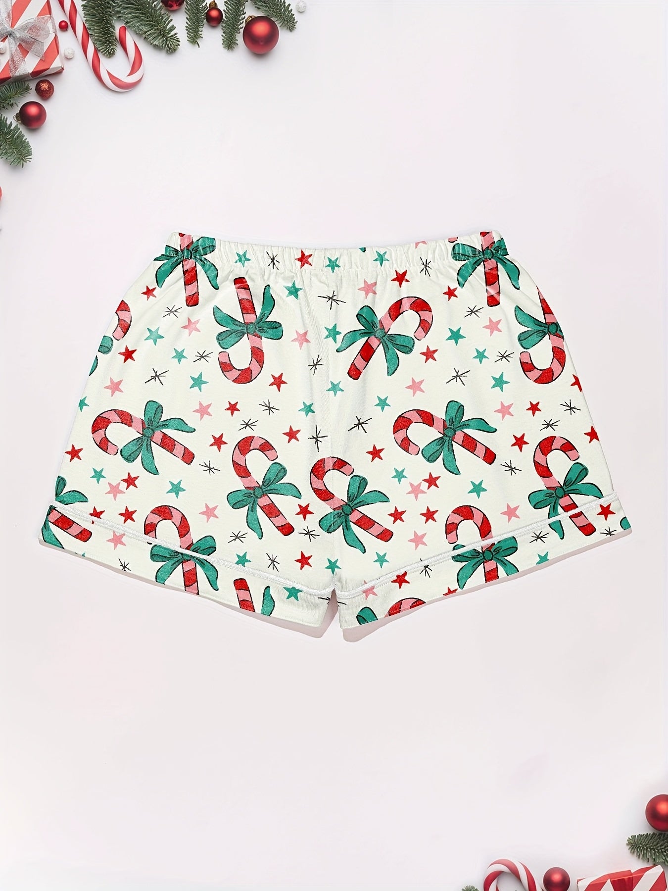Cream cotton pajama set with candy‑cane and green bow print — short‑sleeve button top and elastic waist shorts with piping