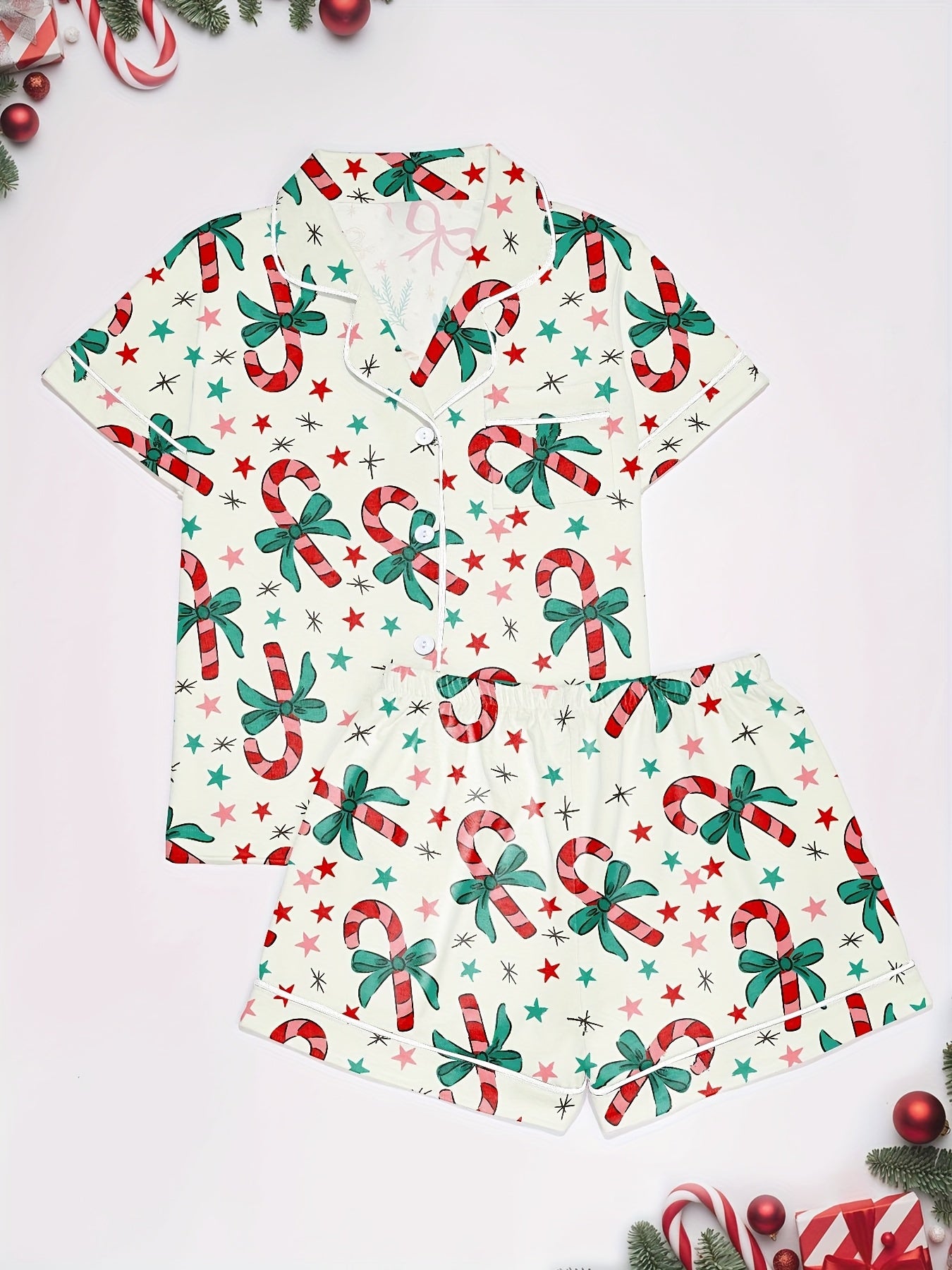 Cream cotton pajama set with candy‑cane and green bow print — short‑sleeve button top and elastic waist shorts with piping