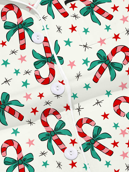 Cream cotton pajama set with candy‑cane and green bow print — short‑sleeve button top and elastic waist shorts with piping