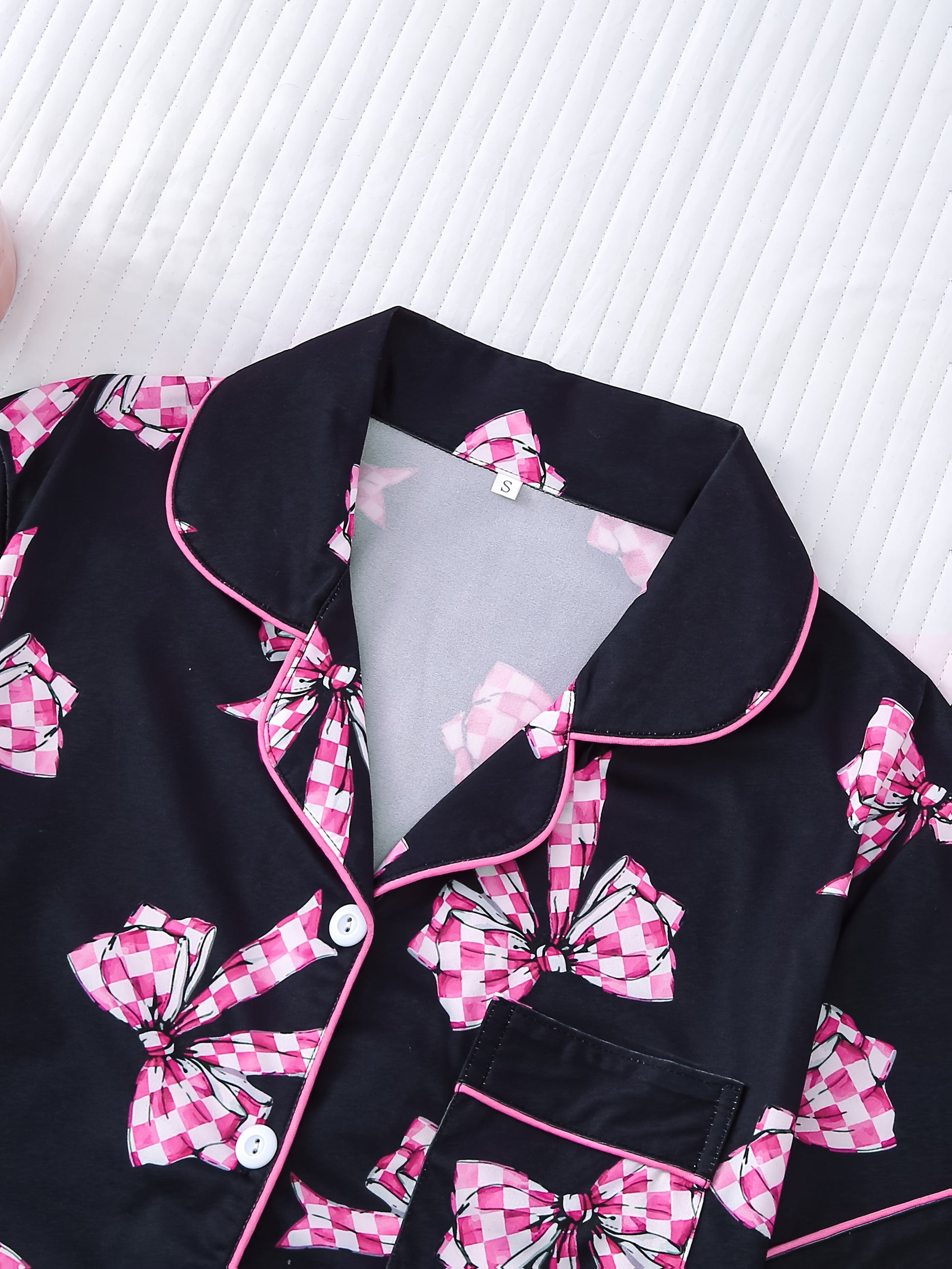 Black satin-look pajama set with pink-check bow print, piped trim, short sleeve button top and elastic waist shorts in silky stretch fabric — 95% Polyester/5% Elastane