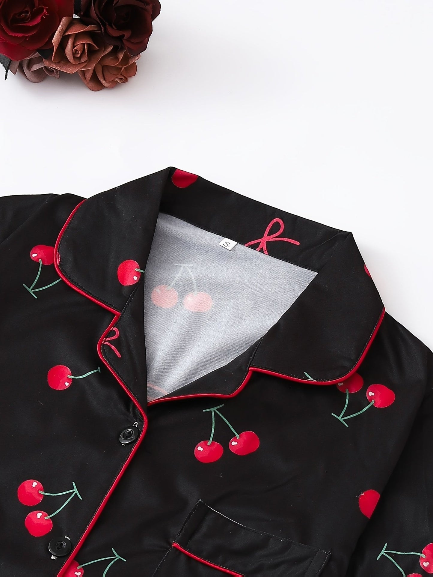 Black satin-look short-sleeve pajama set with red cherry print, piped trim, chest pocket and elastic waist shorts in 95% Polyester 5% Elastane