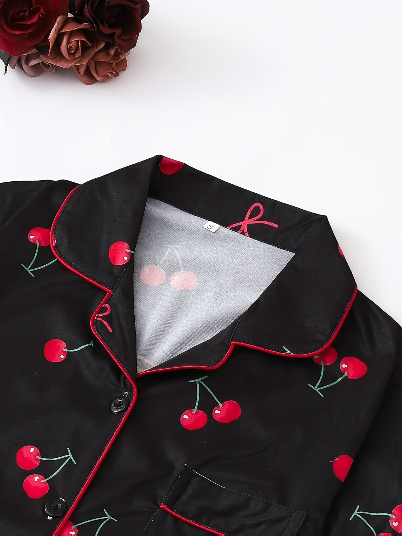 Black satin-look short-sleeve pajama set with red cherry print, piped trim, chest pocket and elastic waist shorts in 95% Polyester 5% Elastane