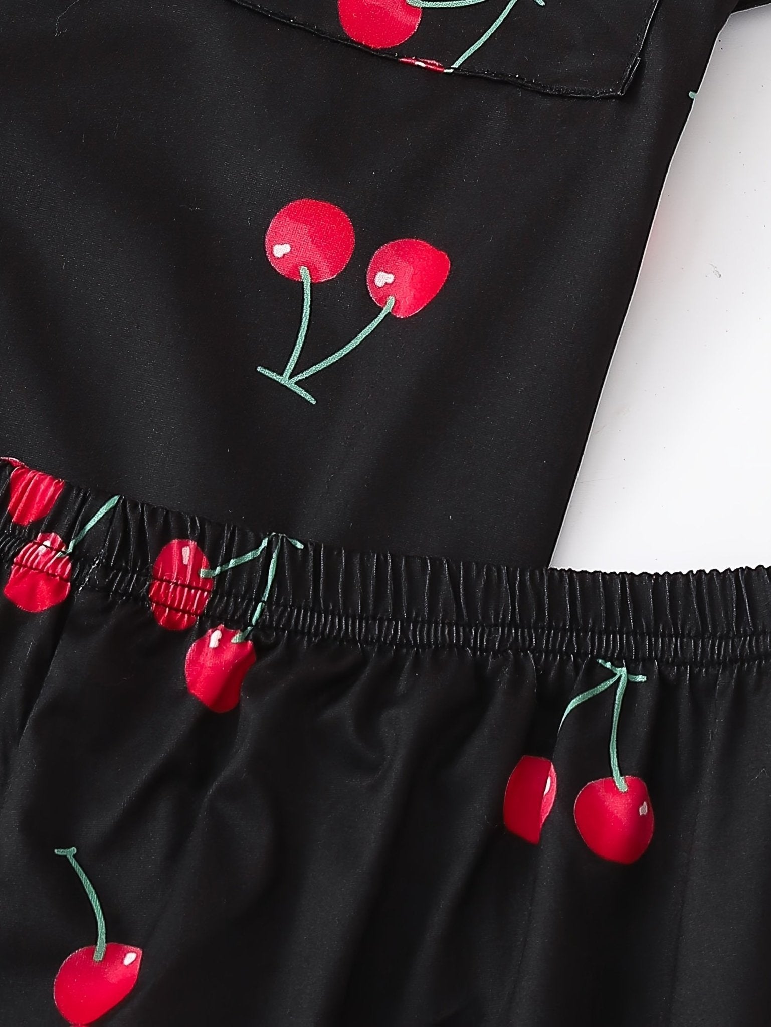 Black satin-look short-sleeve pajama set with red cherry print, piped trim, chest pocket and elastic waist shorts in 95% Polyester 5% Elastane