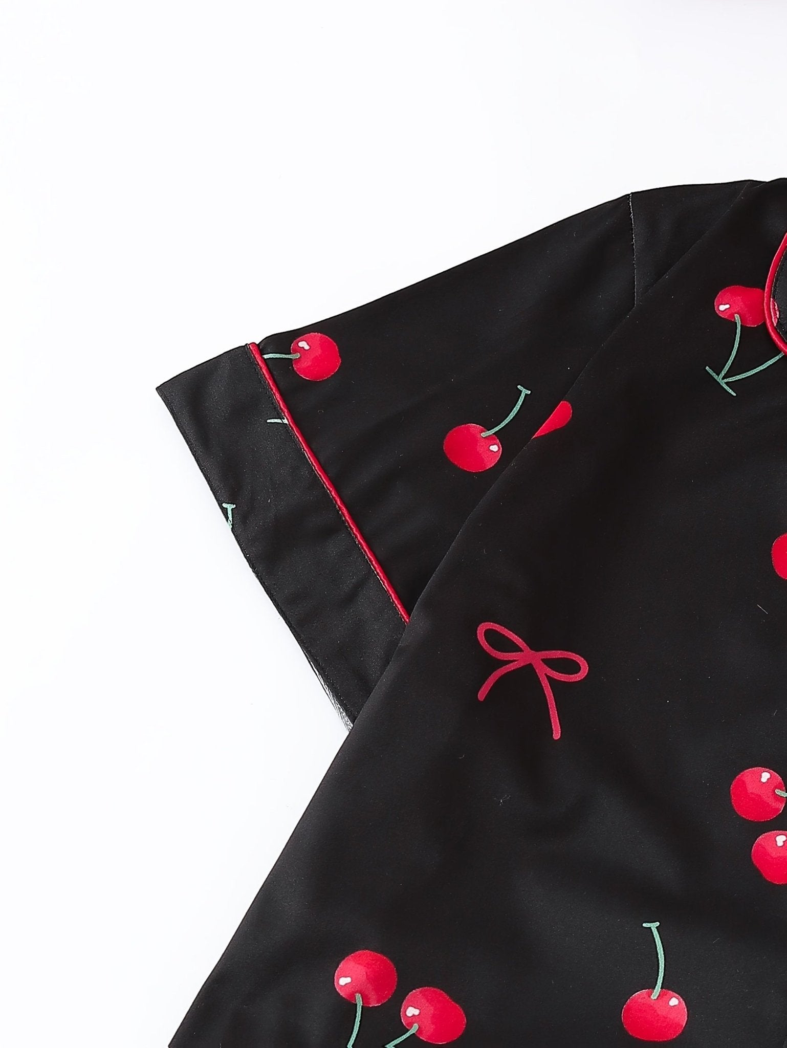 Black satin-look short-sleeve pajama set with red cherry print, piped trim, chest pocket and elastic waist shorts in 95% Polyester 5% Elastane