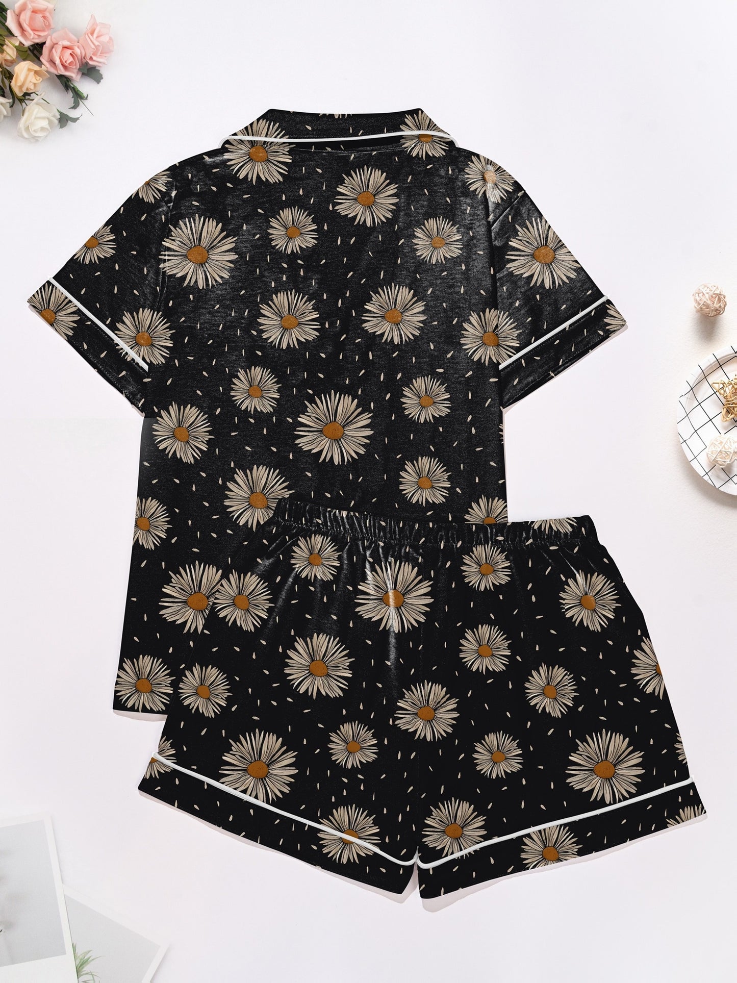 Black short-sleeve modal pajama set with cream daisy print — button-up top and elastic waist shorts with white piping