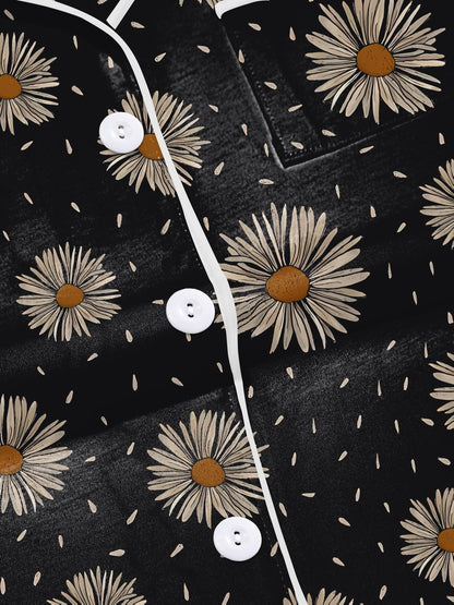 Black short-sleeve modal pajama set with cream daisy print — button-up top and elastic waist shorts with white piping