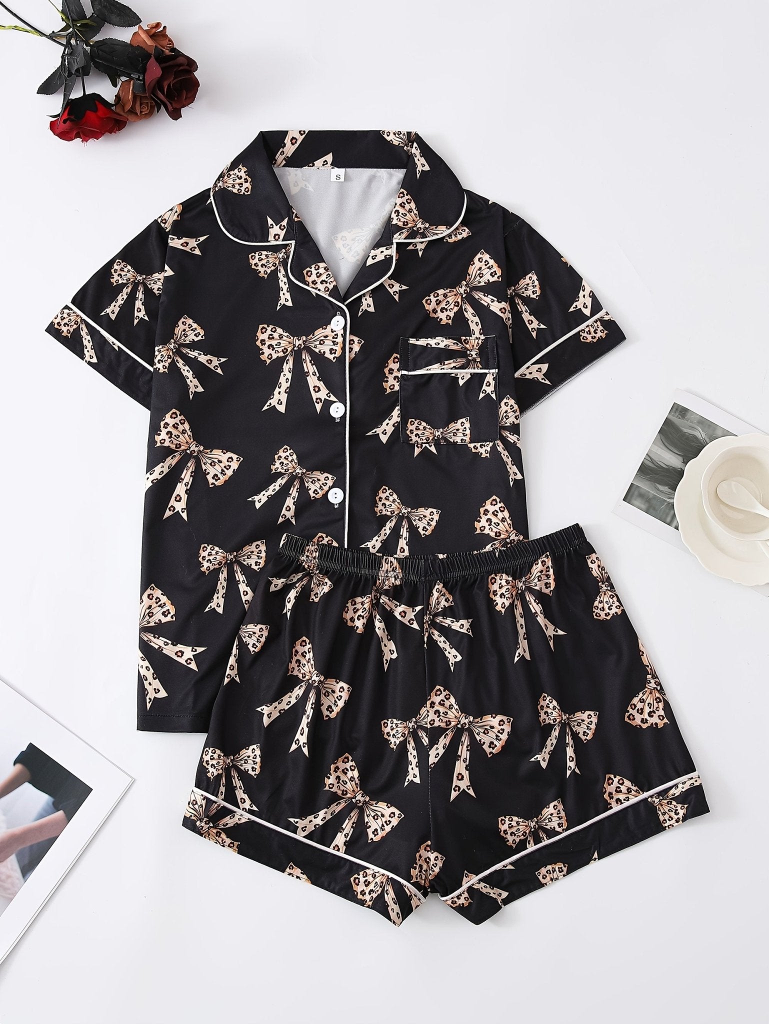 Black satin-look short-sleeve pajama set with beige leopard bow print, piped trim, chest pocket and elastic waist shorts in 95% Polyester 5% Elastane