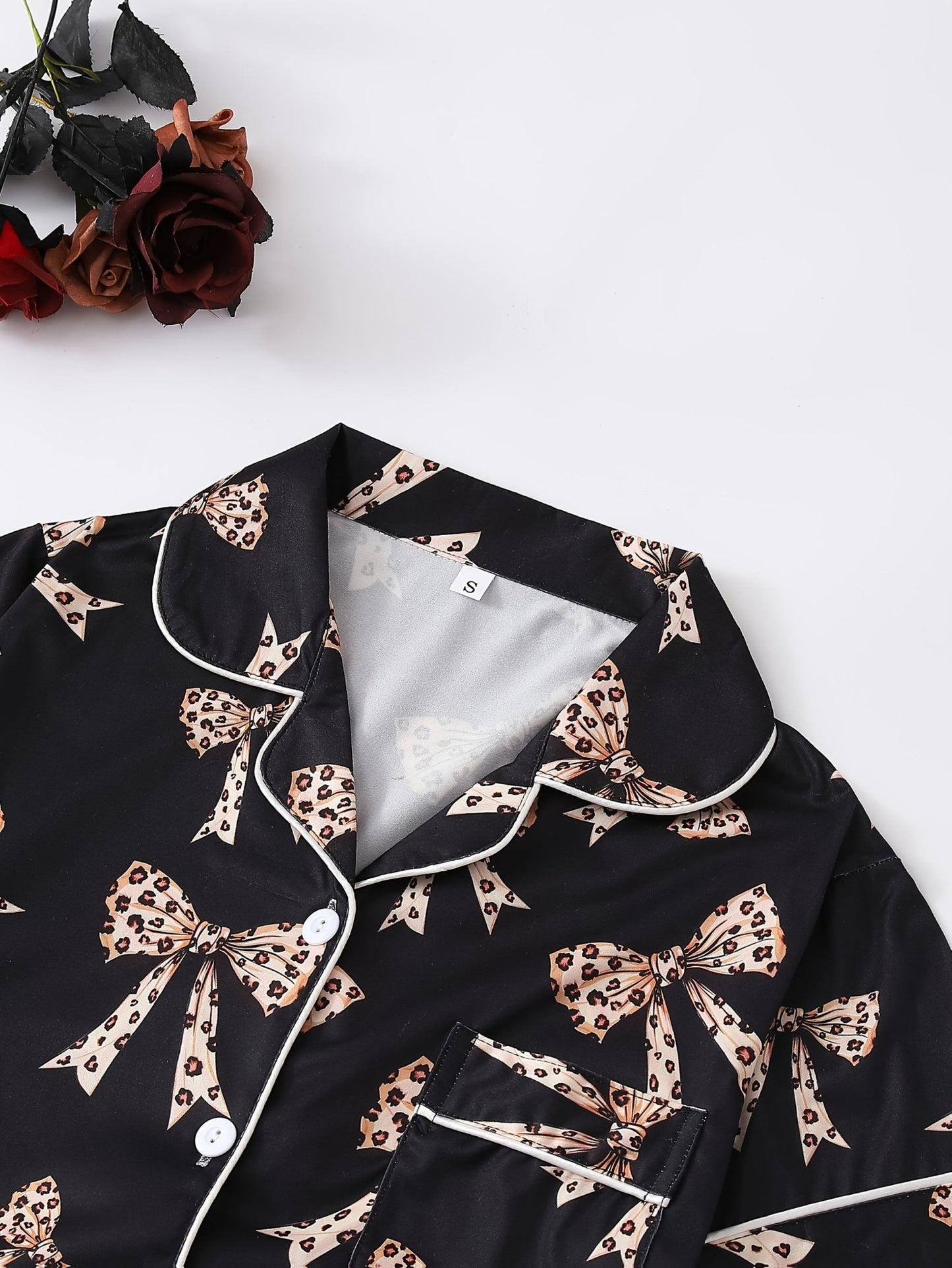 Black satin-look short-sleeve pajama set with beige leopard bow print, piped trim, chest pocket and elastic waist shorts in 95% Polyester 5% Elastane