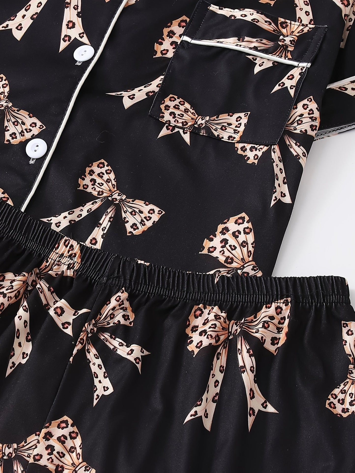 Black satin-look short-sleeve pajama set with beige leopard bow print, piped trim, chest pocket and elastic waist shorts in 95% Polyester 5% Elastane