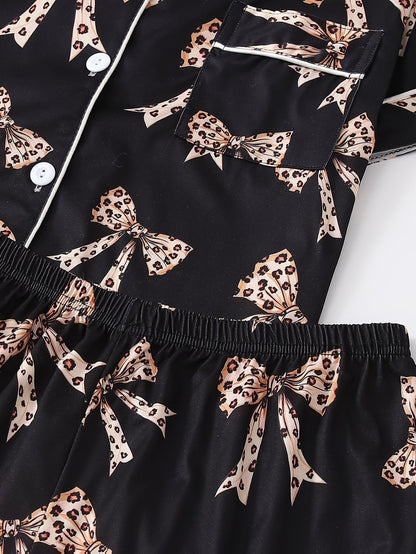 Black satin-look short-sleeve pajama set with beige leopard bow print, piped trim, chest pocket and elastic waist shorts in 95% Polyester 5% Elastane