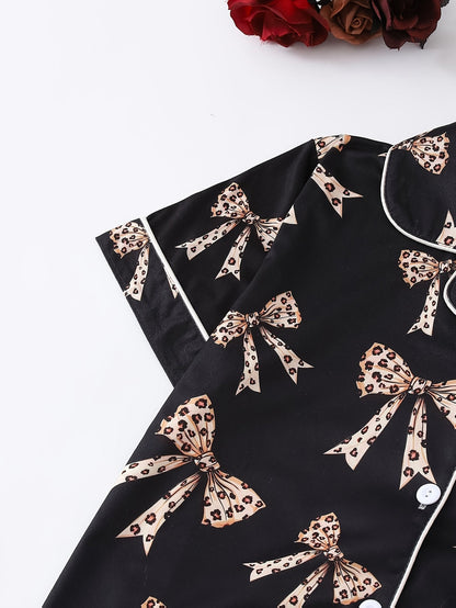 Black satin-look short-sleeve pajama set with beige leopard bow print, piped trim, chest pocket and elastic waist shorts in 95% Polyester 5% Elastane