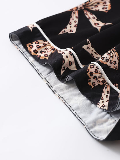 Black satin-look short-sleeve pajama set with beige leopard bow print, piped trim, chest pocket and elastic waist shorts in 95% Polyester 5% Elastane