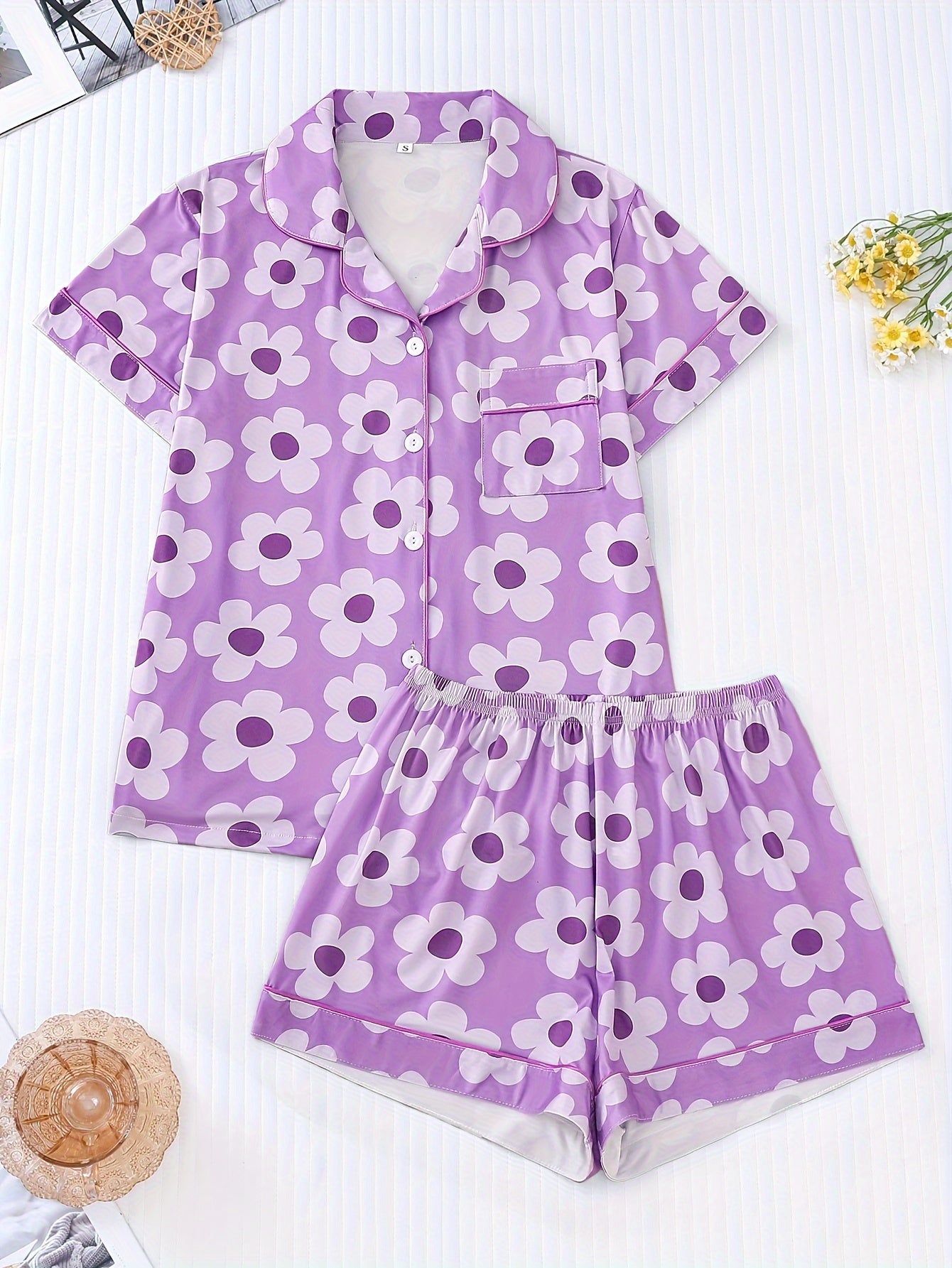 Powder satin-look pajama set with white daisy print — short-sleeve button-up top with chest pocket and elastic waist shorts, 95% Polyester/5% Elastane