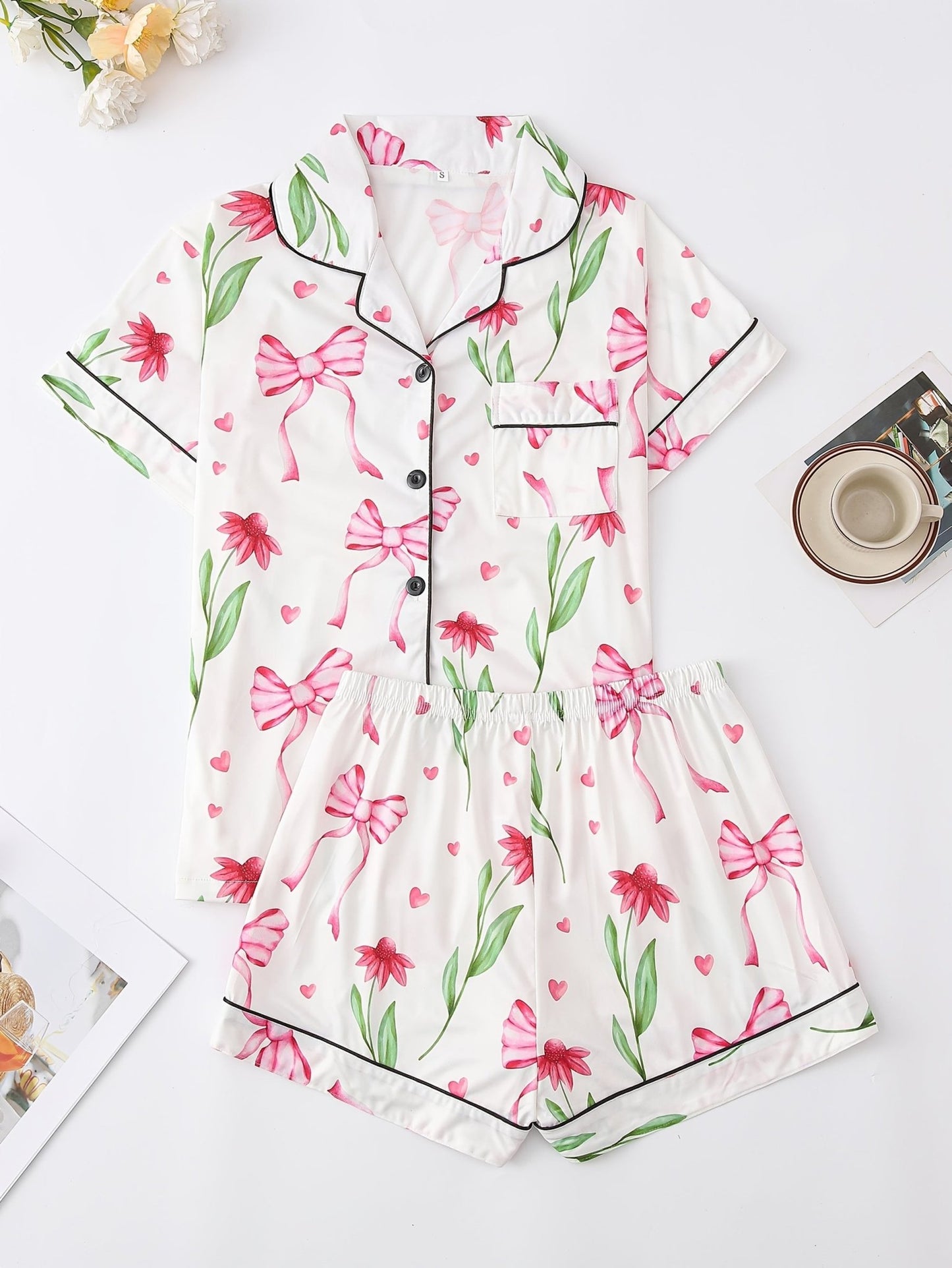 White satin-look short-sleeve pajama set with pink bow and floral print, piped trim, chest pocket and elastic waist shorts in 95% Polyester 5% Elastane — travel-ready silky stretch loungewear