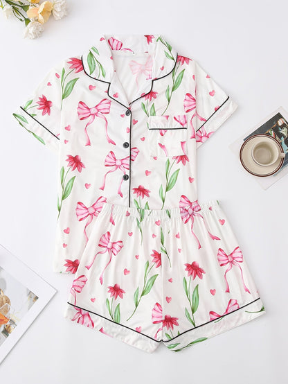 White satin-look short-sleeve pajama set with pink bow and floral print, piped trim, chest pocket and elastic waist shorts in 95% Polyester 5% Elastane — travel-ready silky stretch loungewear