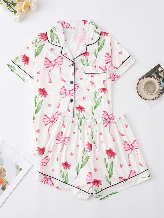 White satin-look short-sleeve pajama set with pink bow and floral print, piped trim, chest pocket and elastic waist shorts in 95% Polyester 5% Elastane — travel-ready silky stretch loungewear