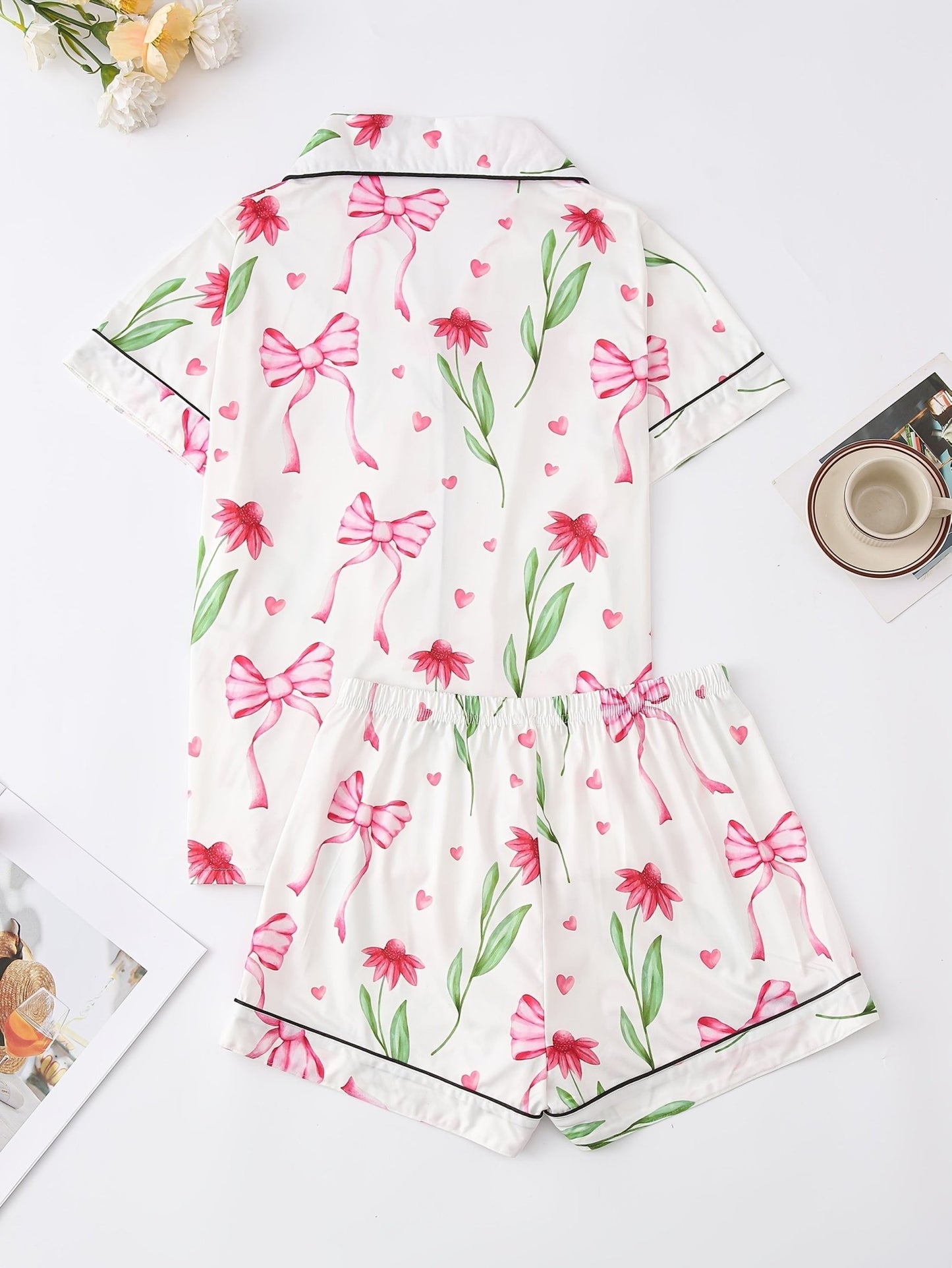 White satin-look short-sleeve pajama set with pink bow and floral print, piped trim, chest pocket and elastic waist shorts in 95% Polyester 5% Elastane — travel-ready silky stretch loungewear