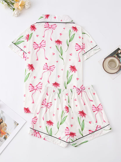 White satin-look short-sleeve pajama set with pink bow and floral print, piped trim, chest pocket and elastic waist shorts in 95% Polyester 5% Elastane — travel-ready silky stretch loungewear