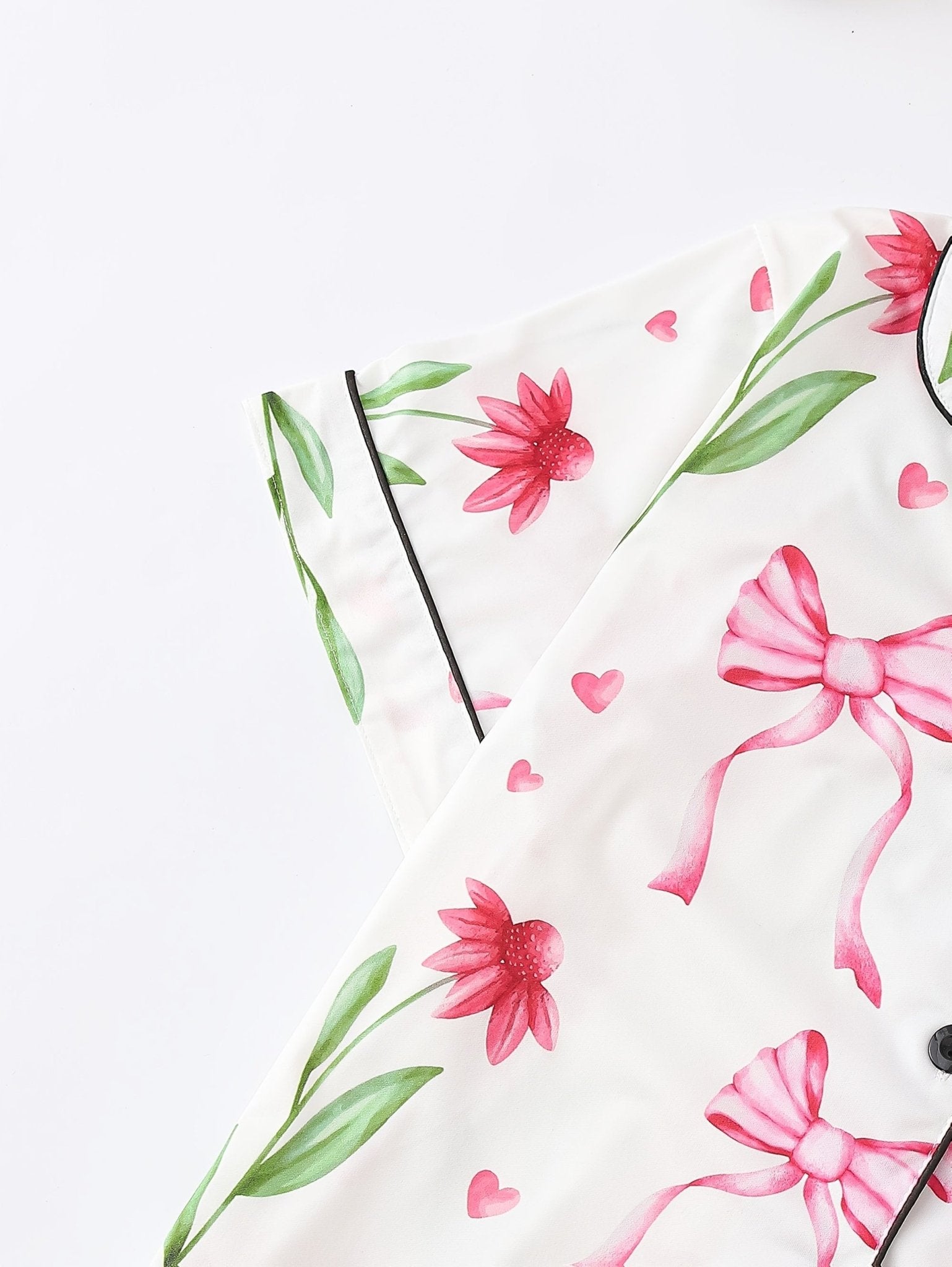 White satin-look short-sleeve pajama set with pink bow and floral print, piped trim, chest pocket and elastic waist shorts in 95% Polyester 5% Elastane — travel-ready silky stretch loungewear