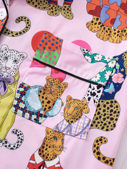 Blush pink satin-look pajama set with colorful leopard illustrations and polka dots — short-sleeve button-up top with chest pocket and elastic waist shorts, 95% Polyester/5% Elastane
