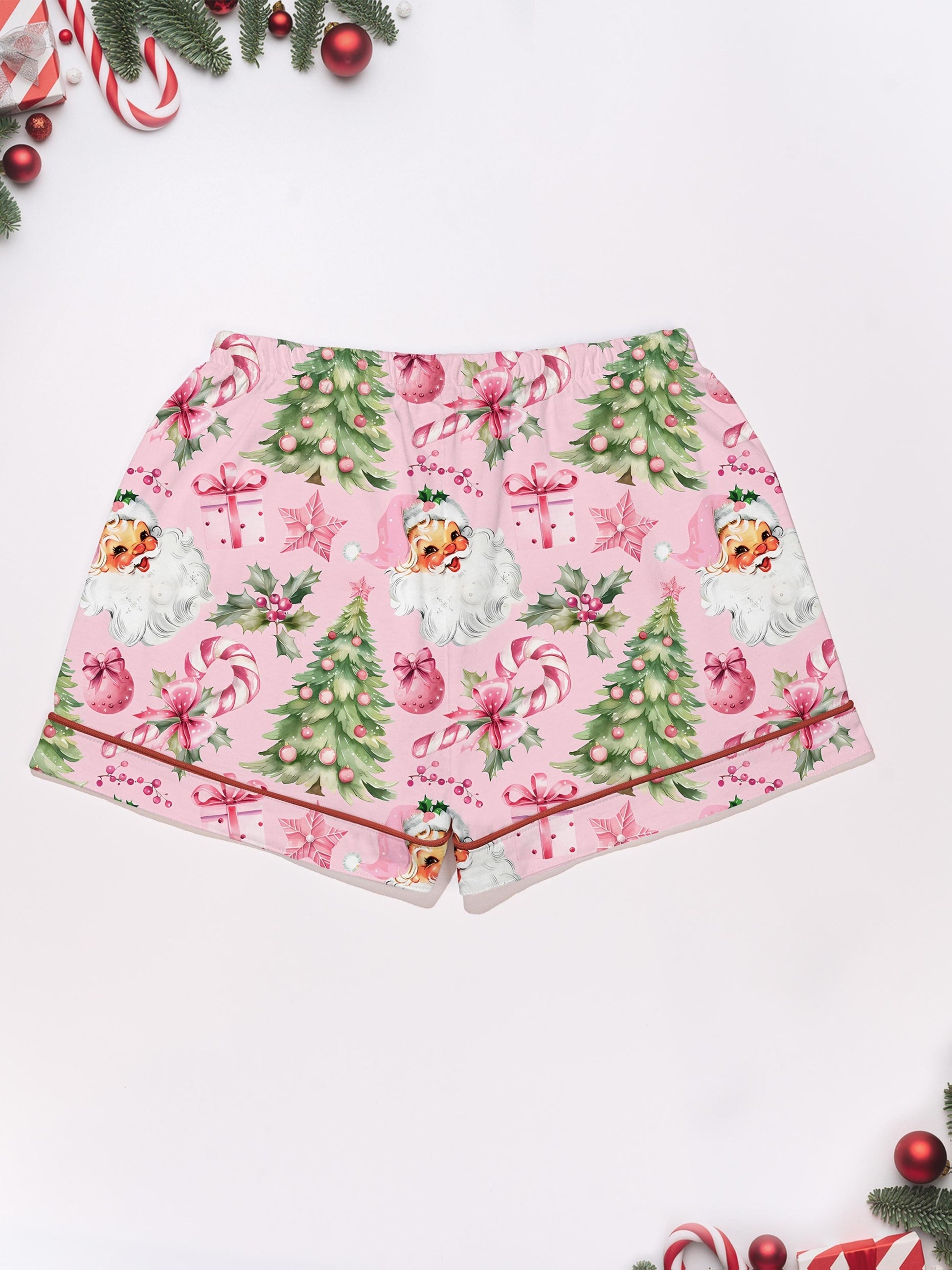 Pastel pink short-sleeve pajama set with vintage Santa faces, decorated Christmas trees and candy cane print — button-up top and elastic waist shorts with contrast piping