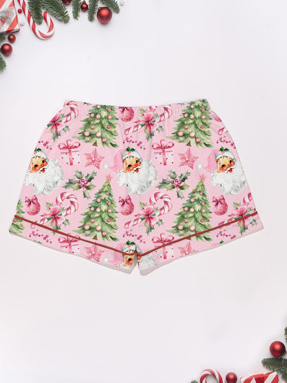 Pastel pink short-sleeve pajama set with vintage Santa faces, decorated Christmas trees and candy cane print — button-up top and elastic waist shorts with contrast piping
