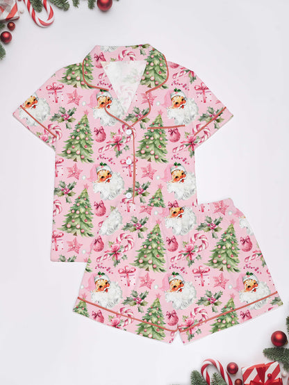 Pastel pink short-sleeve pajama set with vintage Santa faces, decorated Christmas trees and candy cane print — button-up top and elastic waist shorts with contrast piping