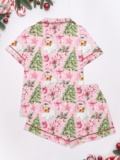 Pastel pink short-sleeve pajama set with vintage Santa faces, decorated Christmas trees and candy cane print — button-up top and elastic waist shorts with contrast piping