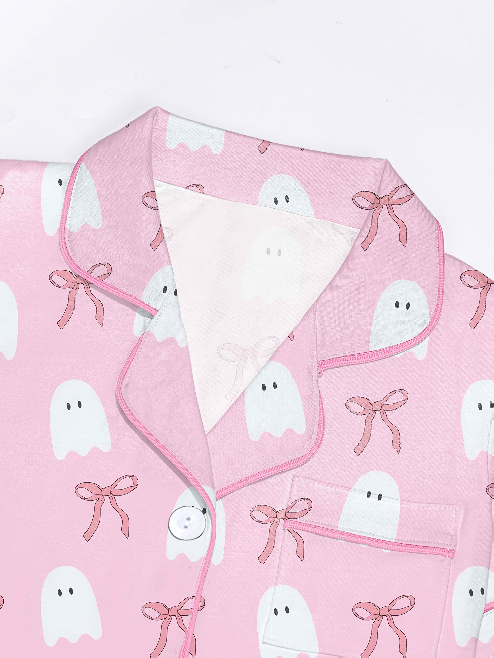 Pink cotton pajama set with white ghost and ribbon print — short sleeve notch collar top and elastic waist shorts