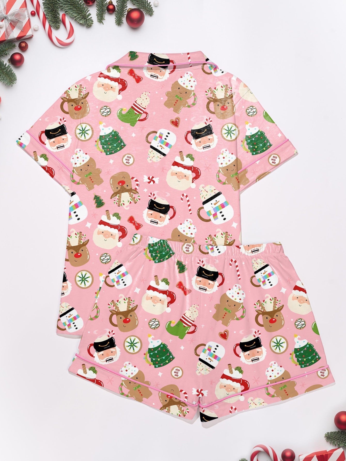 Pink satin‑look sleep shorts with playful Christmas icons — Santa mugs, snowmen, gingerbread, reindeer and candy — elastic waist and white piping