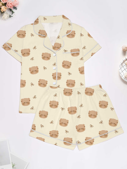 Cream short‑sleeve modal pajama set with teddy face and bow print — button‑up top and elastic waist shorts with piping