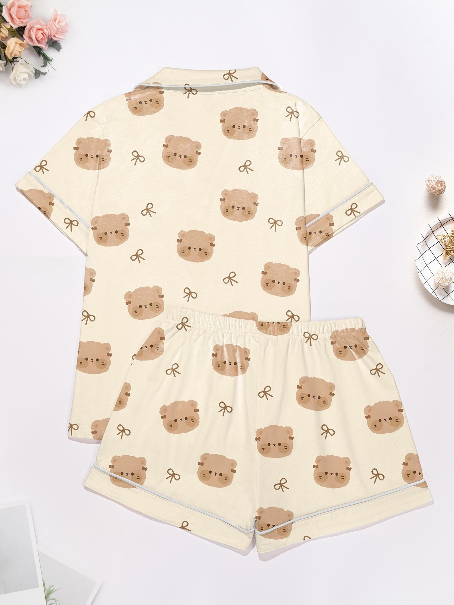 Cream short‑sleeve modal pajama set with teddy face and bow print — button‑up top and elastic waist shorts with piping