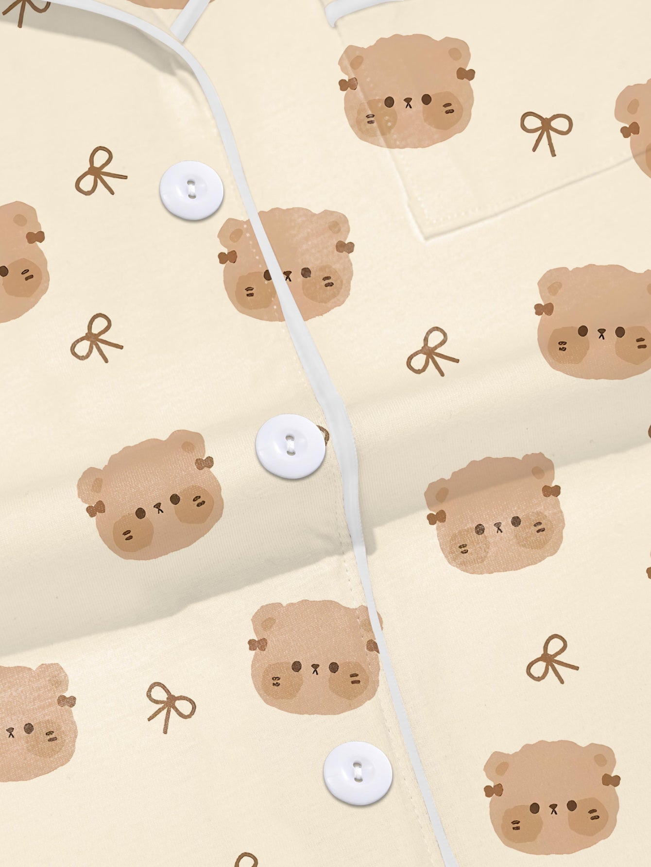 Cream short‑sleeve modal pajama set with teddy face and bow print — button‑up top and elastic waist shorts with piping