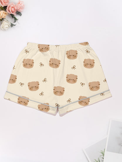 Cream short‑sleeve modal pajama set with teddy face and bow print — button‑up top and elastic waist shorts with piping
