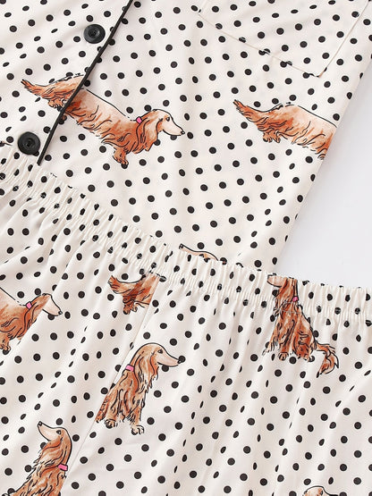 Cream and black polka dot satin-look pajama set with dachshund print, piped trim, chest pocket and elastic waist shorts in 95% Polyester 5% Elastane — silky stretch travel-ready loungewear