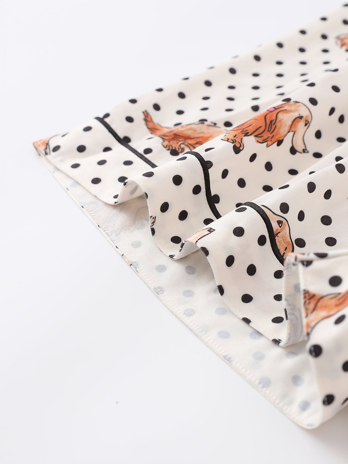 Cream and black polka dot satin-look pajama set with dachshund print, piped trim, chest pocket and elastic waist shorts in 95% Polyester 5% Elastane — silky stretch travel-ready loungewear
