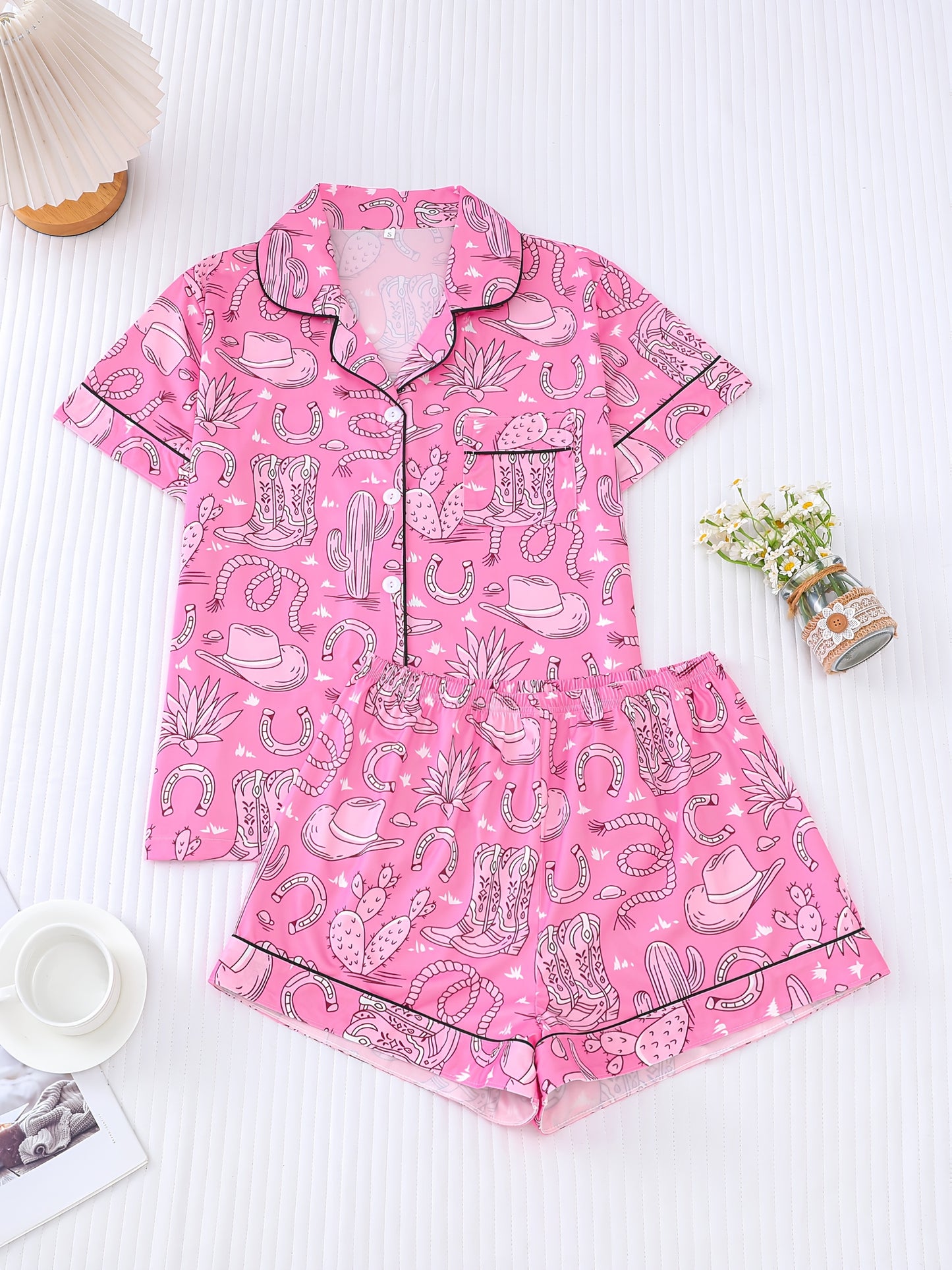 Bubblegum pink satin-look short pajama set with cowboy boots, hats and cactus print — button-up short-sleeve top with chest pocket and elastic waist shorts, 95% Polyester/5% Elastane