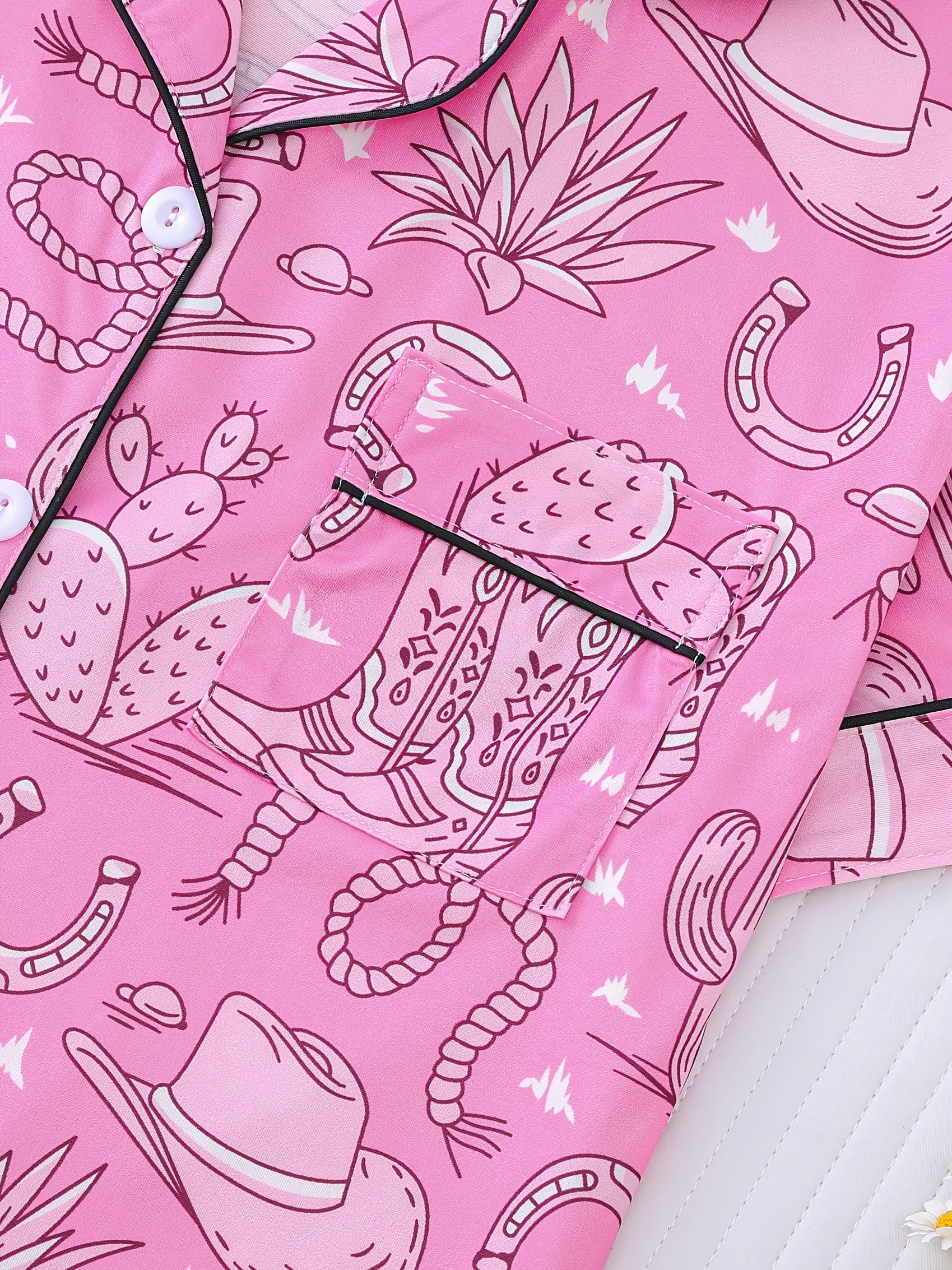Bubblegum pink satin-look short pajama set with cowboy boots, hats and cactus print — button-up short-sleeve top with chest pocket and elastic waist shorts, 95% Polyester/5% Elastane