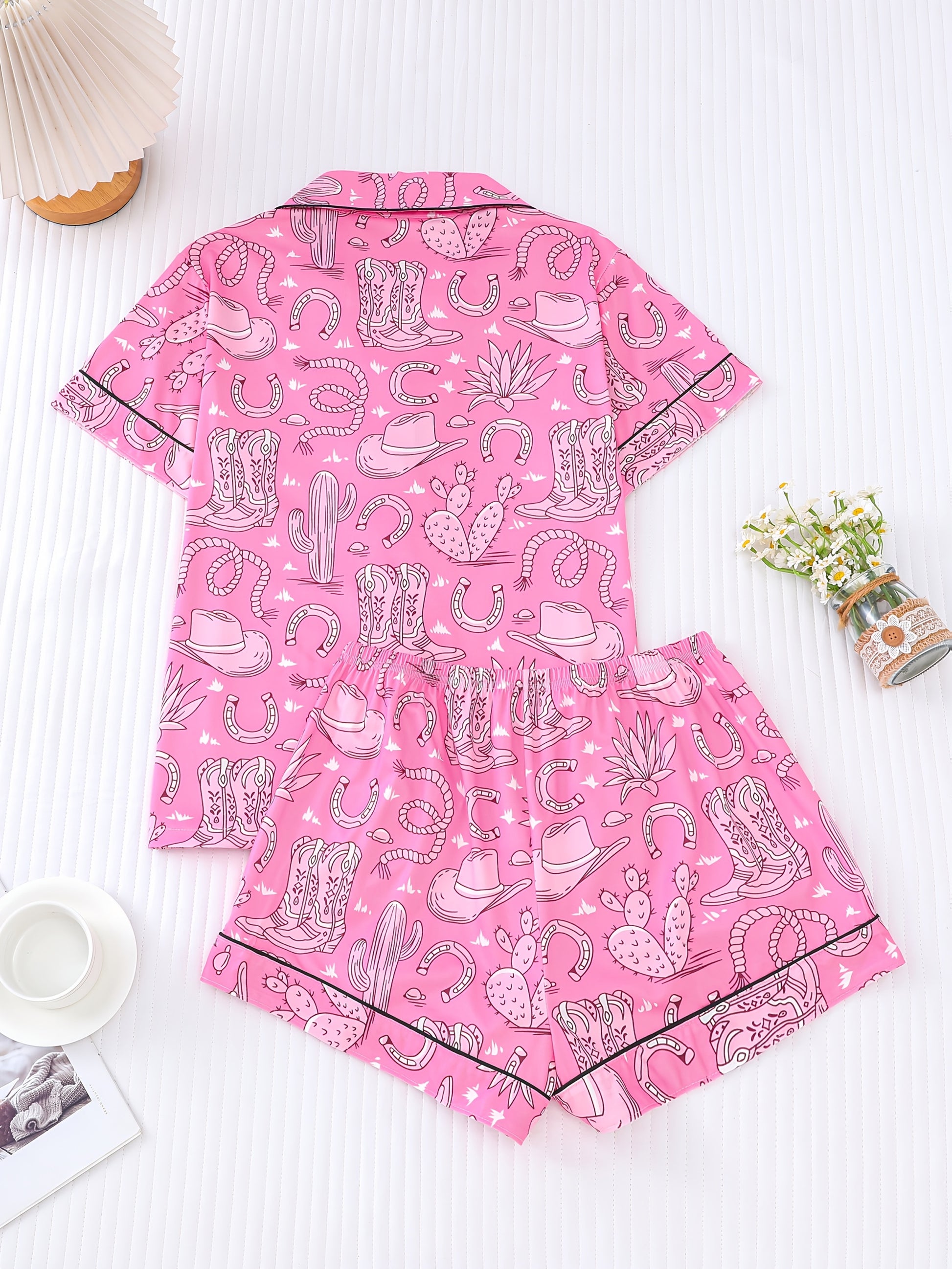 Bubblegum pink satin-look short pajama set with cowboy boots, hats and cactus print — button-up short-sleeve top with chest pocket and elastic waist shorts, 95% Polyester/5% Elastane