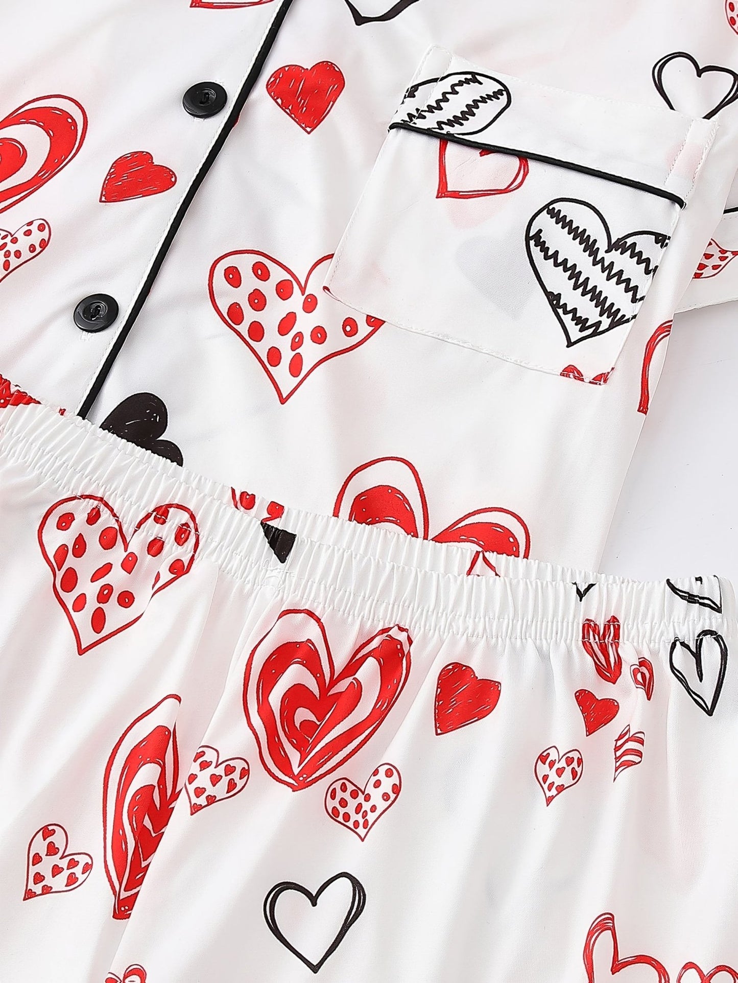 White satin-look short-sleeve pajama set with red and black hand-drawn heart print, piped trim, chest pocket and elastic waist shorts in 95% Polyester 5% Elastane — silky stretch travel-ready loungewear
