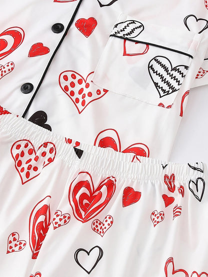 White satin-look short-sleeve pajama set with red and black hand-drawn heart print, piped trim, chest pocket and elastic waist shorts in 95% Polyester 5% Elastane — silky stretch travel-ready loungewear