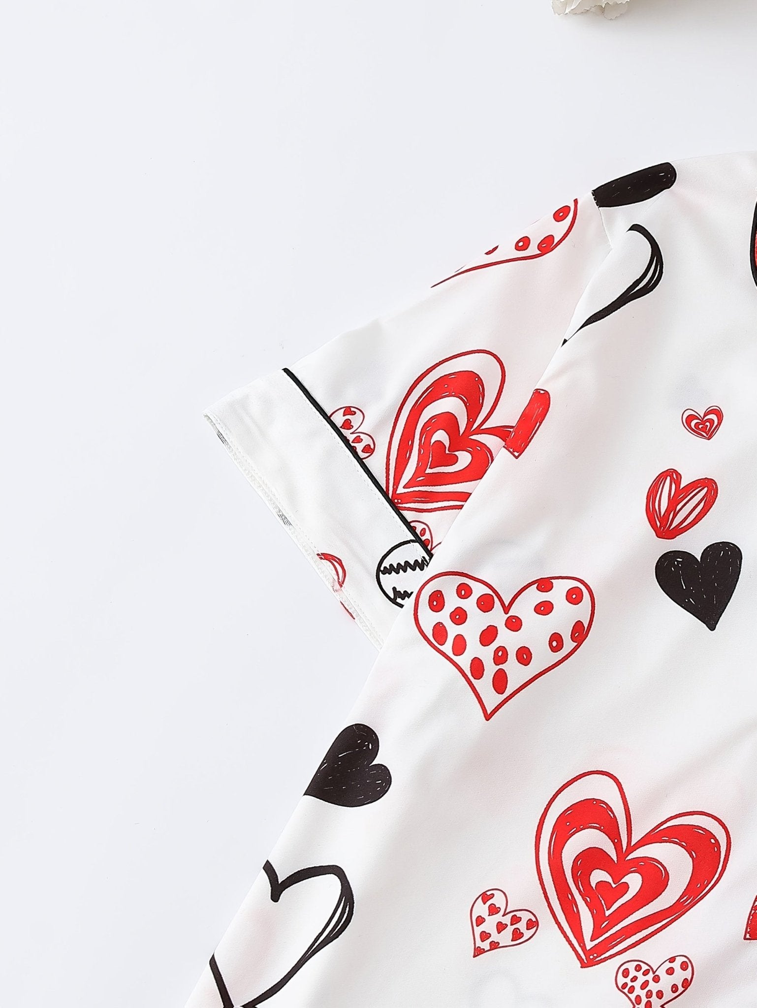 White satin-look short-sleeve pajama set with red and black hand-drawn heart print, piped trim, chest pocket and elastic waist shorts in 95% Polyester 5% Elastane — silky stretch travel-ready loungewear