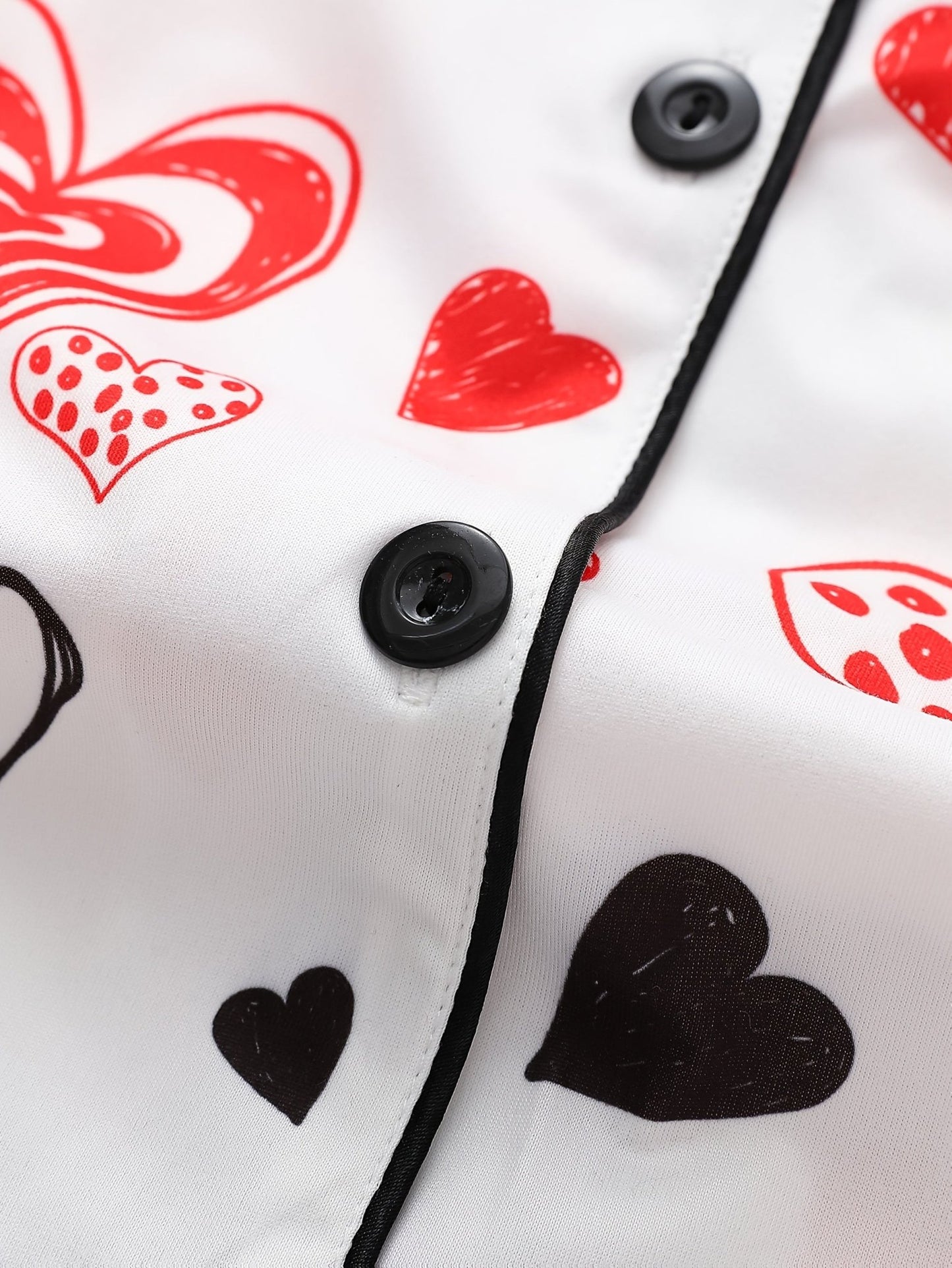 White satin-look short-sleeve pajama set with red and black hand-drawn heart print, piped trim, chest pocket and elastic waist shorts in 95% Polyester 5% Elastane — silky stretch travel-ready loungewear