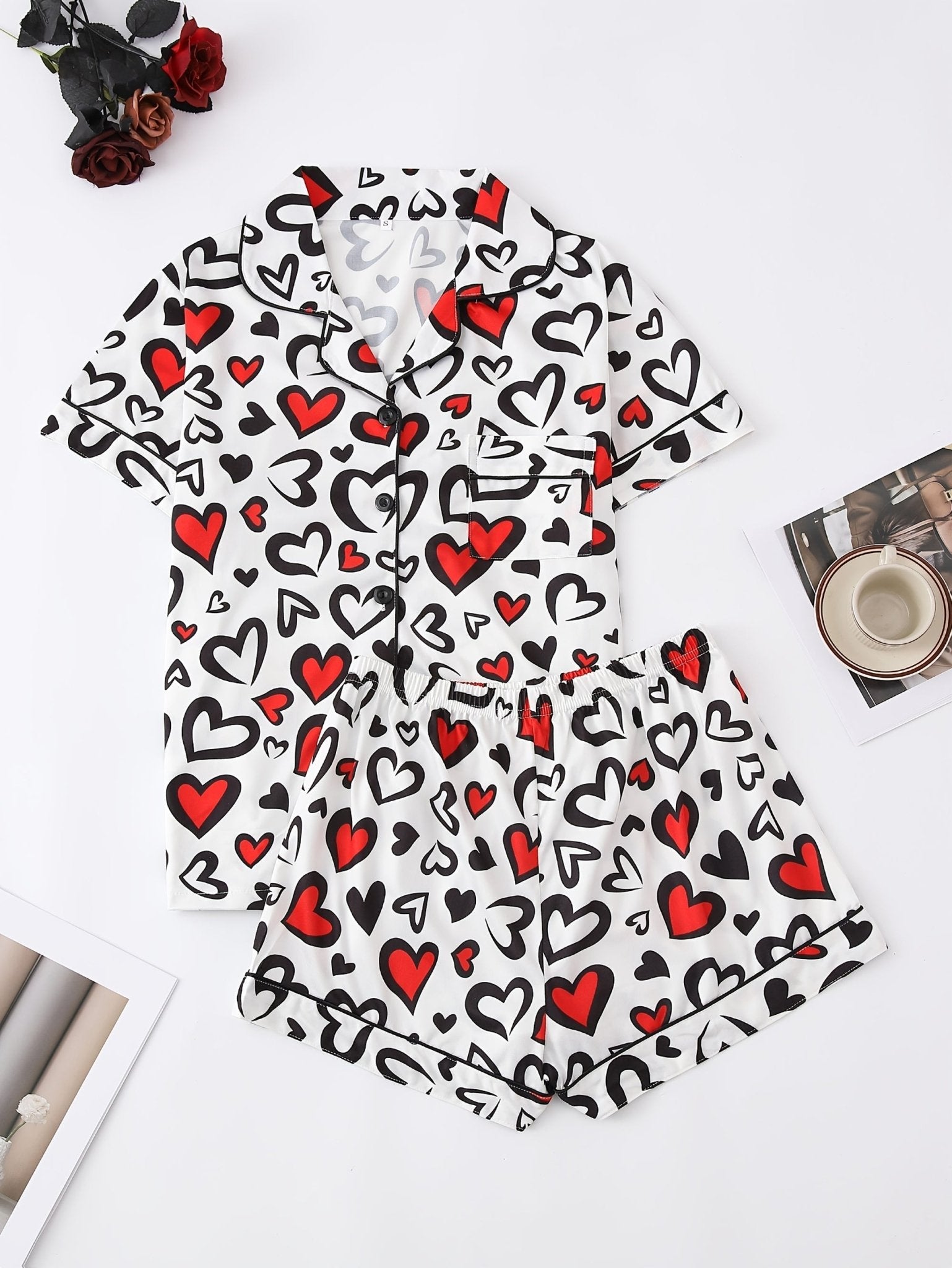 White satin-look short-sleeve pajama set with red and black heart print, piped trim, chest pocket and elastic waist shorts in 95% Polyester 5% Elastane — silky stretch travel-ready loungewear